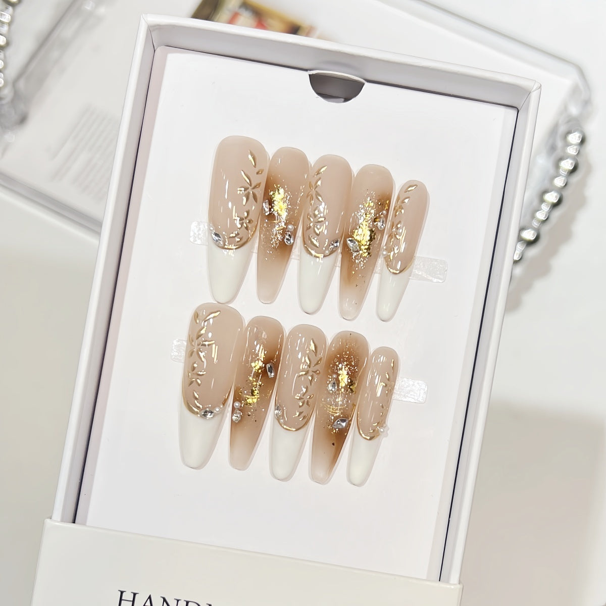 Hand-painted French tip press-on nails with gold foil and rhinestone accents