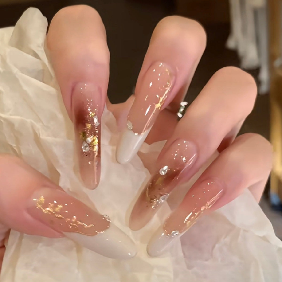 Hand-painted French tip press-on nails with gold foil and rhinestone accents model hand show