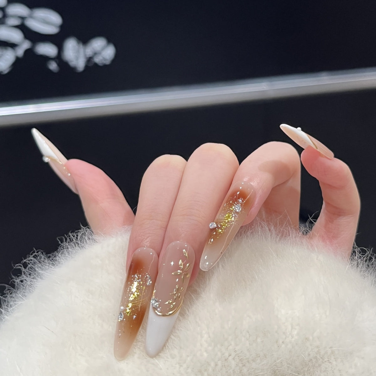 Hand-painted French tip press-on nails with gold foil and rhinestone accents model hand show